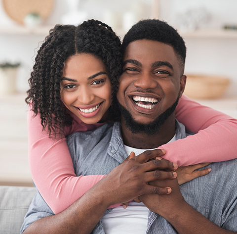 Smiling woman hugging a smiling man from behind