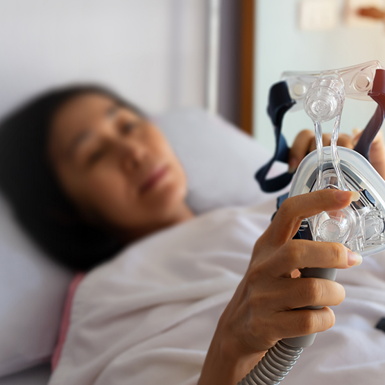 Woman in bed holding a CPAP mask