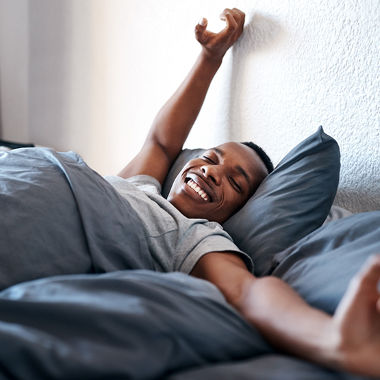 Man smiling while stretching in bed