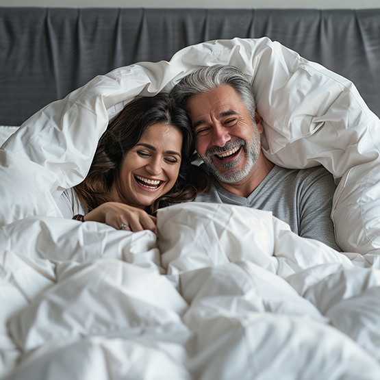 Smiling man and woman laying in bed together