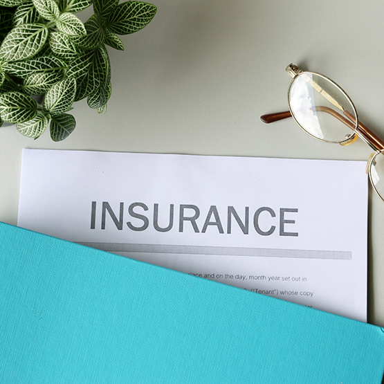 Insurance paperwork on a desk next to a pair of glasses