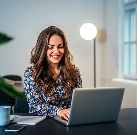 Woman smiling while taking a sleep apnea quiz on her laptop