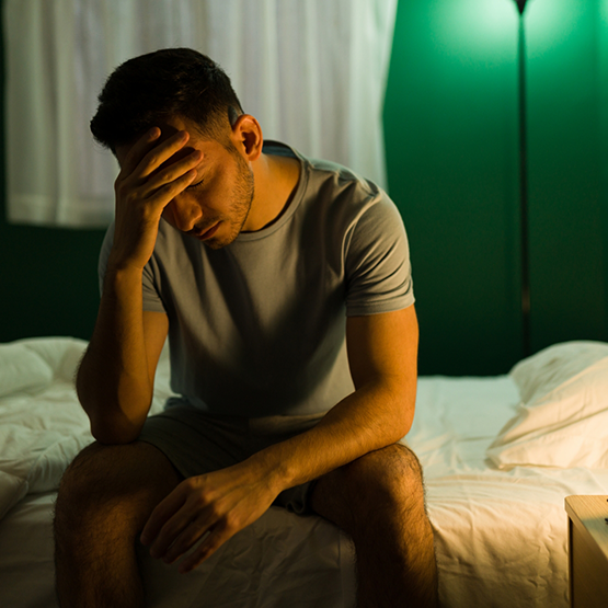 Man sitting on his bed with his head in his hand