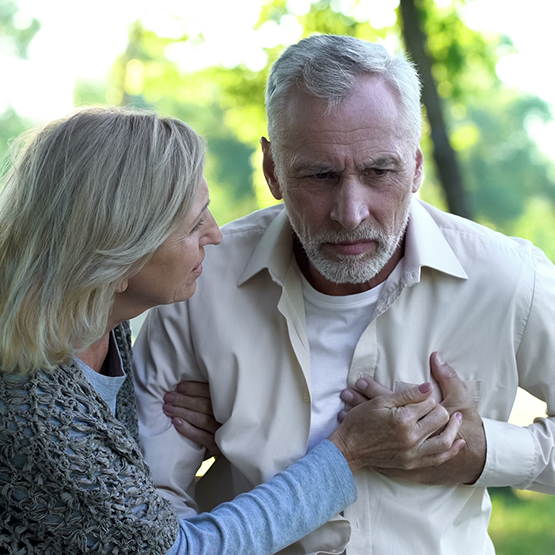 Senior man clutching his chest while walking with a senior woman