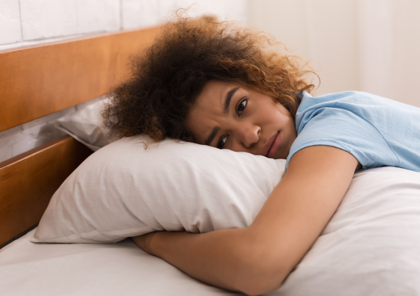 Woman holding pillow, struggling to sleep