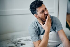 Man sitting up in bed, yawning