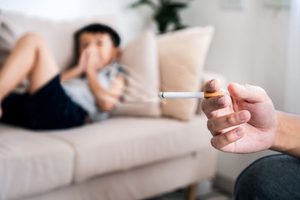 Child covering nose while nearby adult smokes